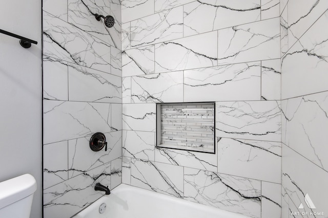 bathroom featuring tiled shower / bath combo and toilet