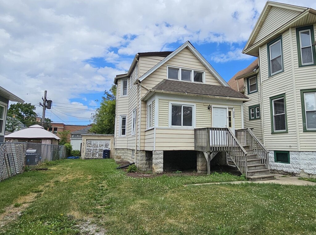 rear view of house with a yard, an outbuilding, and central AC unit