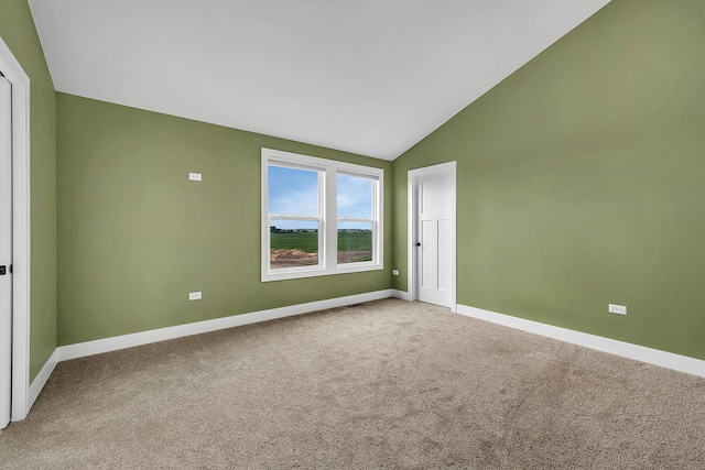 spare room featuring light carpet and vaulted ceiling