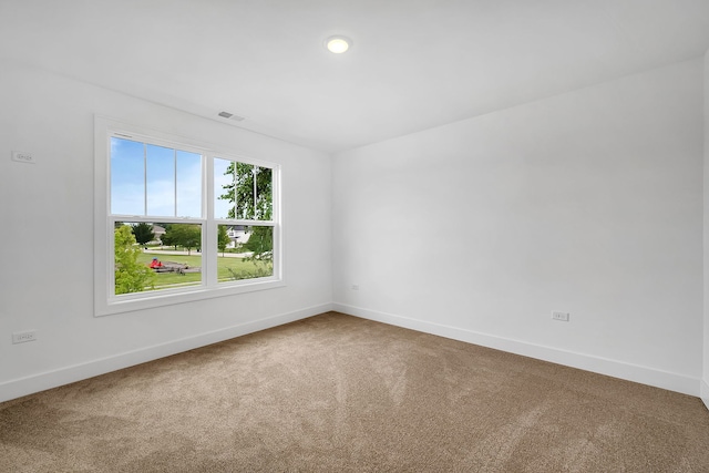 empty room with carpet, visible vents, and baseboards