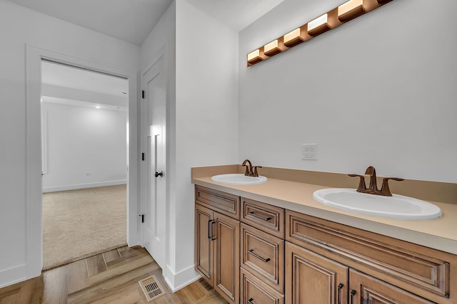 bathroom featuring double vanity, a sink, visible vents, and baseboards