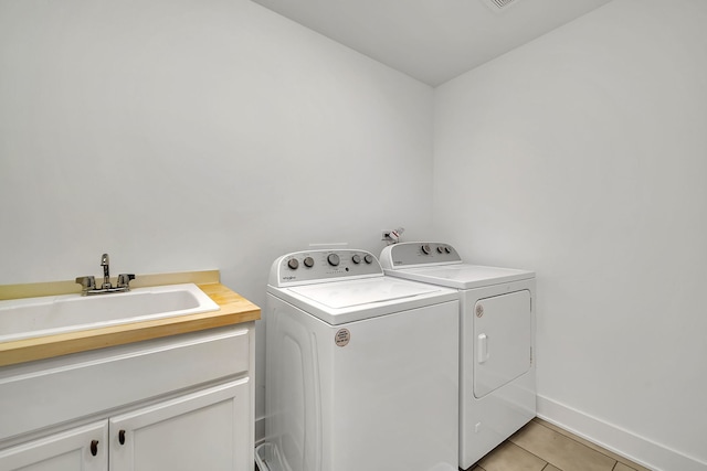 washroom featuring sink, cabinets, washer and dryer, and light tile patterned floors