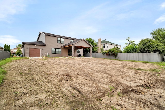 rear view of property with a garage and fence