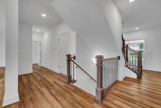 hallway with recessed lighting, baseboards, an upstairs landing, and wood finished floors