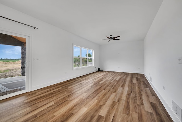 interior space with a ceiling fan, baseboards, visible vents, and wood finished floors