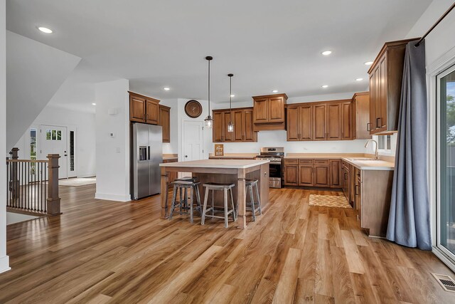 kitchen featuring light hardwood / wood-style floors, a center island, plenty of natural light, and stainless steel appliances