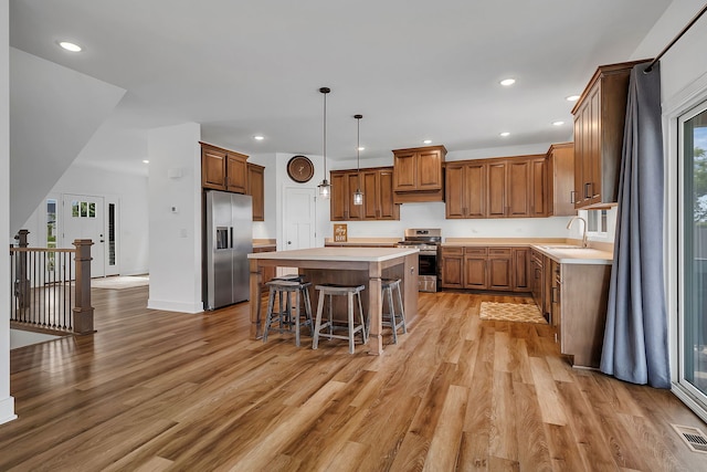 kitchen featuring appliances with stainless steel finishes, a center island, light countertops, and a sink