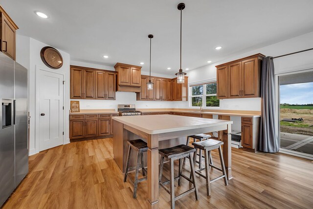 kitchen featuring stainless steel appliances, pendant lighting, a center island, a breakfast bar area, and light hardwood / wood-style floors