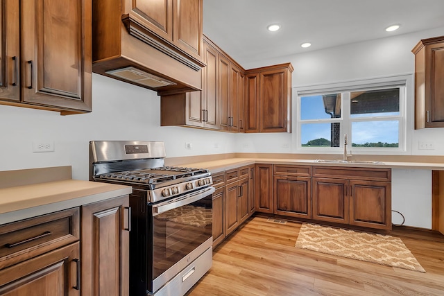 kitchen featuring sink, light hardwood / wood-style flooring, stainless steel gas stove, and custom range hood