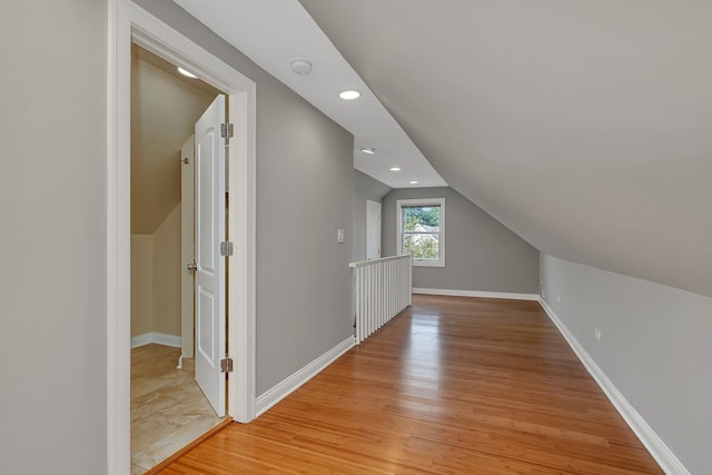 additional living space with light hardwood / wood-style flooring and lofted ceiling