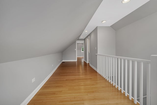 additional living space with light wood-type flooring and vaulted ceiling