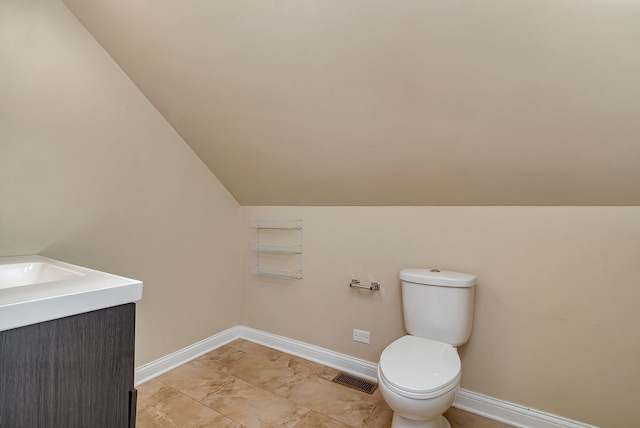 bathroom with tile patterned flooring, toilet, vaulted ceiling, and vanity