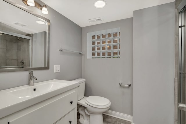 bathroom featuring wood-type flooring, toilet, walk in shower, and vanity