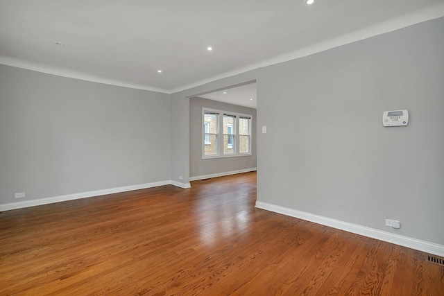 empty room featuring hardwood / wood-style flooring and crown molding