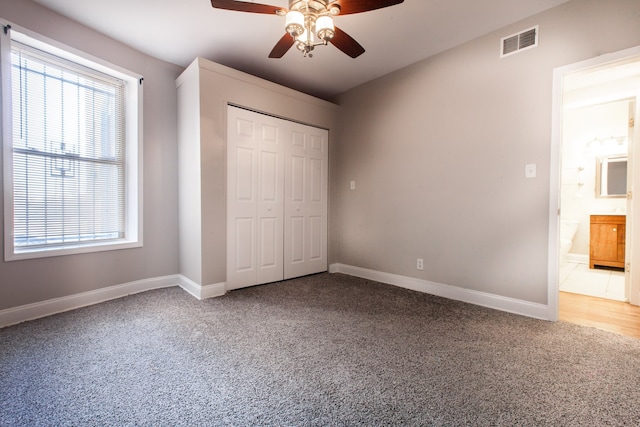 unfurnished bedroom featuring ceiling fan, carpet flooring, ensuite bathroom, and a closet