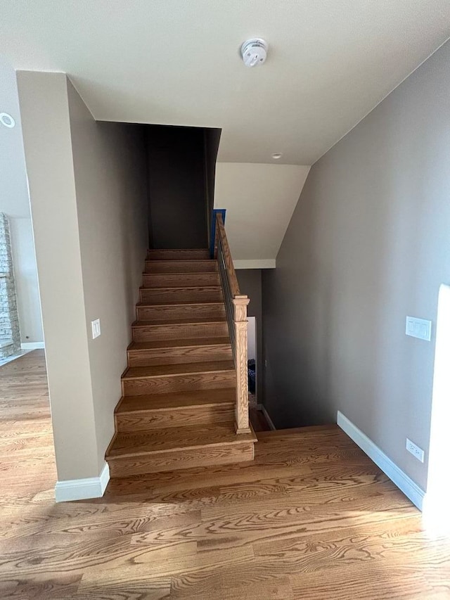 staircase with vaulted ceiling and hardwood / wood-style floors