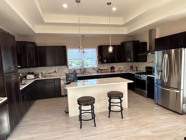 kitchen with stainless steel fridge with ice dispenser, a breakfast bar area, a center island, range with gas stovetop, and a raised ceiling