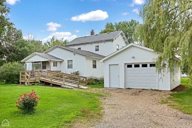 rear view of house with a deck, driveway, a lawn, and an outbuilding