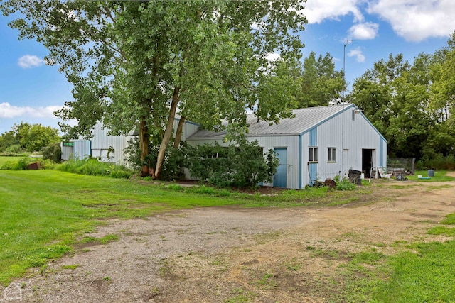 exterior space with an outdoor structure, an outbuilding, a detached garage, and dirt driveway