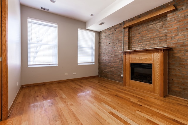 unfurnished living room featuring brick wall and hardwood / wood-style floors