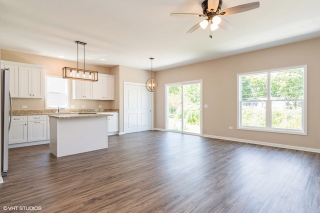 kitchen featuring pendant lighting, white cabinetry, a center island, and ceiling fan with notable chandelier