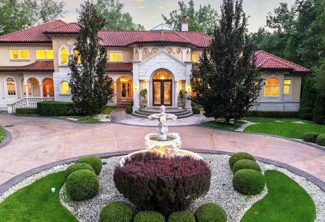 mediterranean / spanish home with stone siding, curved driveway, a chimney, and a tile roof