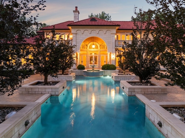 view of pool with french doors and a pool with connected hot tub