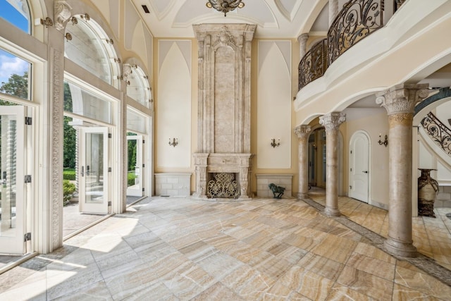 foyer with decorative columns, plenty of natural light, and a towering ceiling