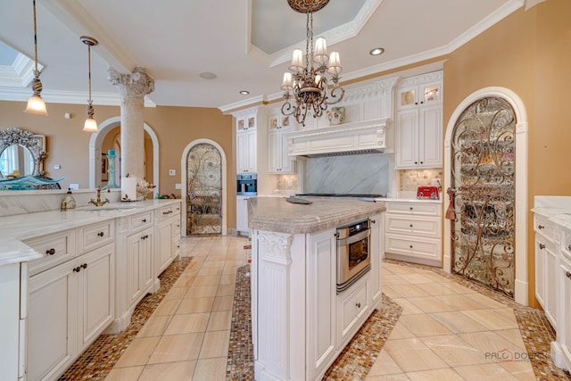 kitchen featuring a kitchen island, a tray ceiling, a sink, crown molding, and backsplash