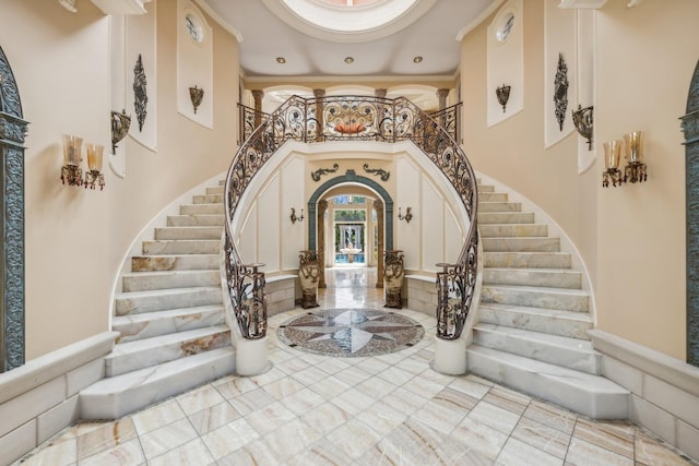 foyer with stairway, arched walkways, a towering ceiling, and crown molding