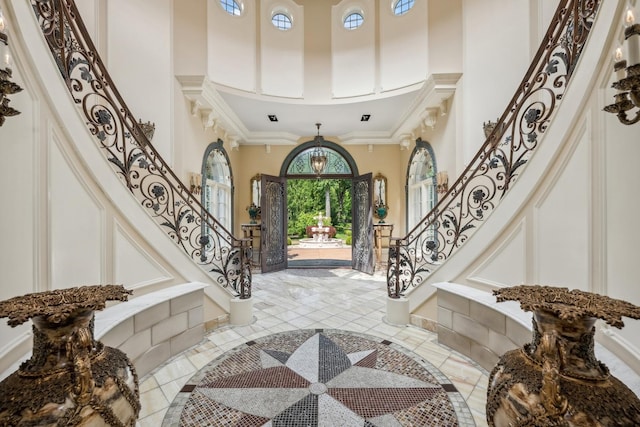 foyer entrance with stairs, a high ceiling, and ornamental molding