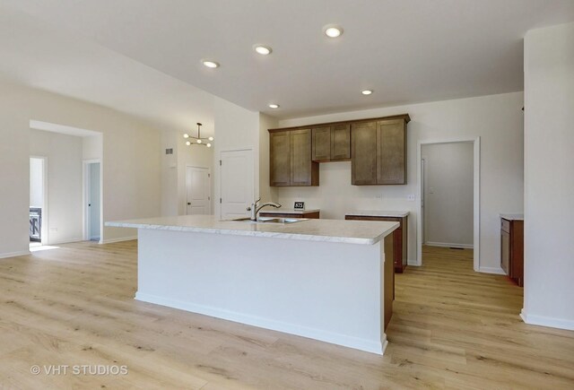 kitchen featuring a chandelier, light hardwood / wood-style flooring, a kitchen island with sink, and sink