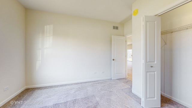 unfurnished bedroom with a closet and light colored carpet