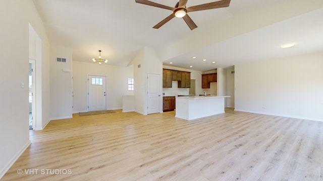 unfurnished living room featuring ceiling fan with notable chandelier, sink, and light wood-type flooring