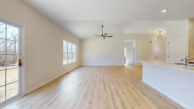 unfurnished living room featuring lofted ceiling, light hardwood / wood-style floors, and ceiling fan with notable chandelier