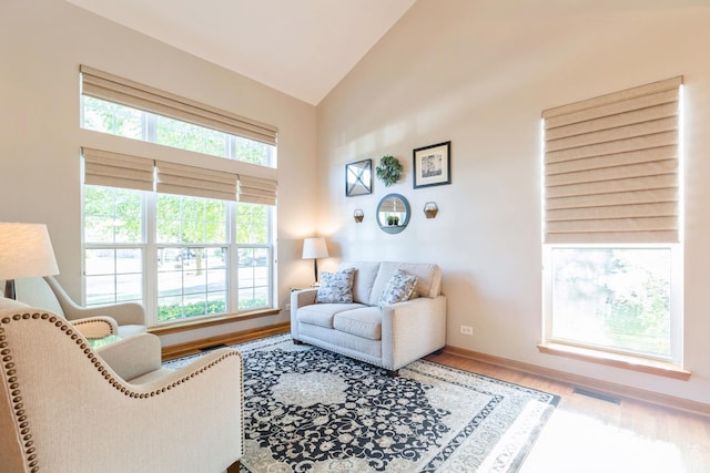 living room with high vaulted ceiling, plenty of natural light, wood finished floors, and baseboards