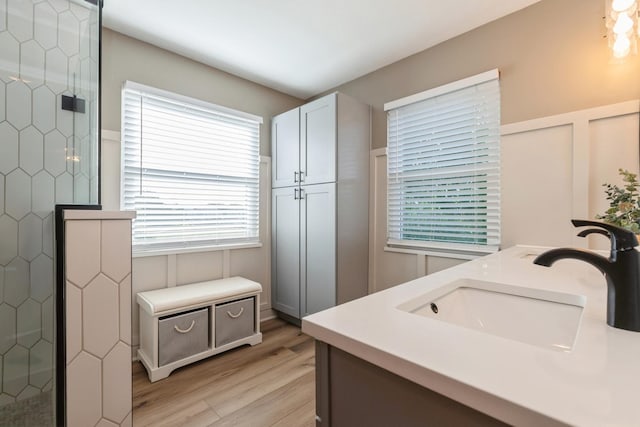 bathroom with double vanity, a shower stall, a sink, and wood finished floors