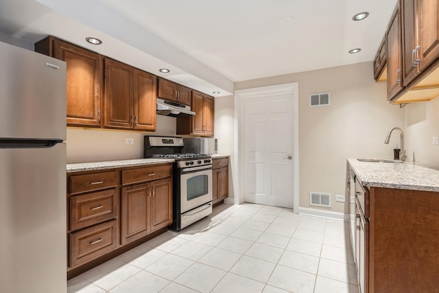 kitchen featuring under cabinet range hood, visible vents, stainless steel appliances, and a sink