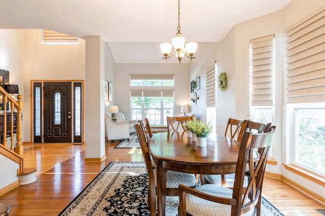 dining space featuring light wood-type flooring, stairway, baseboards, and an inviting chandelier