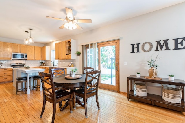 dining area with light wood-type flooring, a ceiling fan, and baseboards