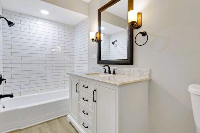 full bathroom with tiled shower / bath combo, vanity, hardwood / wood-style floors, and toilet