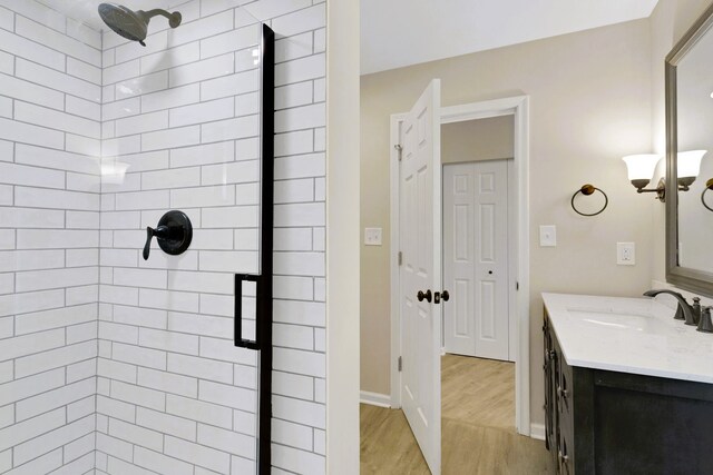 bathroom with vanity, a tile shower, and hardwood / wood-style flooring