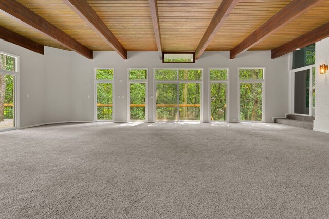 unfurnished living room featuring carpet floors, beamed ceiling, and wooden ceiling