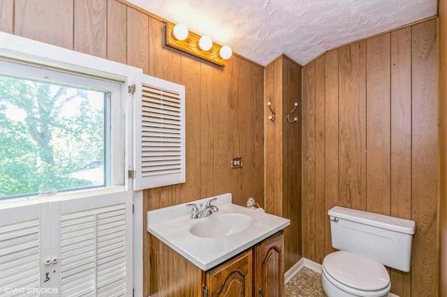 bathroom featuring wood walls, vanity, and toilet