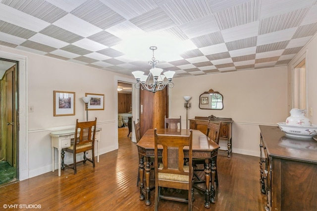 dining room featuring baseboards, wood finished floors, and an inviting chandelier