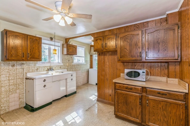 kitchen with brown cabinetry, light countertops, light floors, and white microwave