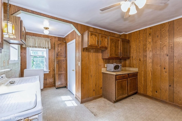 kitchen with wood walls, brown cabinets, light floors, washer / dryer, and crown molding