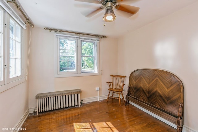 living area featuring radiator heating unit, baseboards, ceiling fan, and wood finished floors