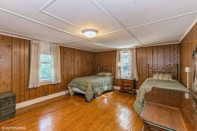 bedroom with wood walls, hardwood / wood-style flooring, and baseboards