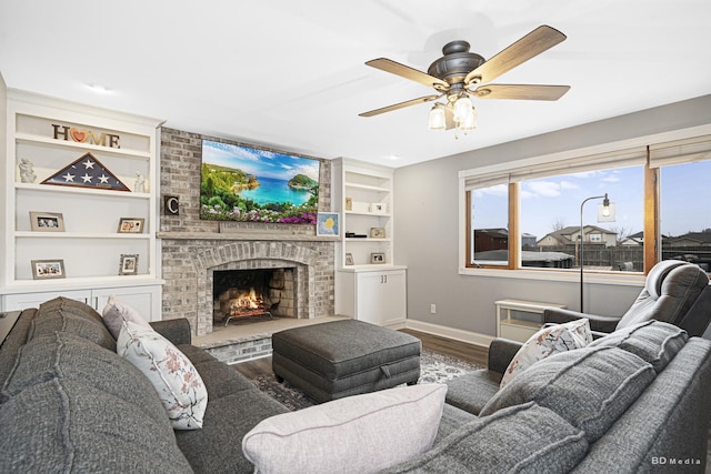 living room with hardwood / wood-style flooring, a brick fireplace, ceiling fan, and built in shelves